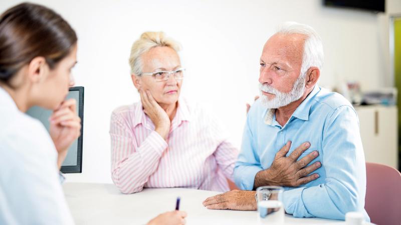 A doctor talks with an mature adult couple during an office visit.