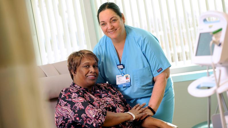 A nurse poses for a photo with a female breast cancer patient.