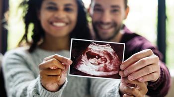 A young couple holds a sonogram print out and are excited to welcome a new baby.