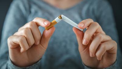 Close-up photo of a person breaking a cigarette in half.