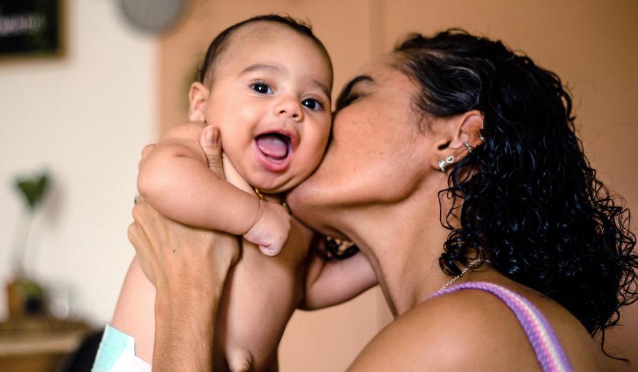 A mother kisses her newborn baby.