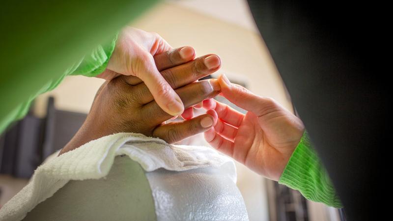 Close up photo of a practitioner examining a patient's hand.