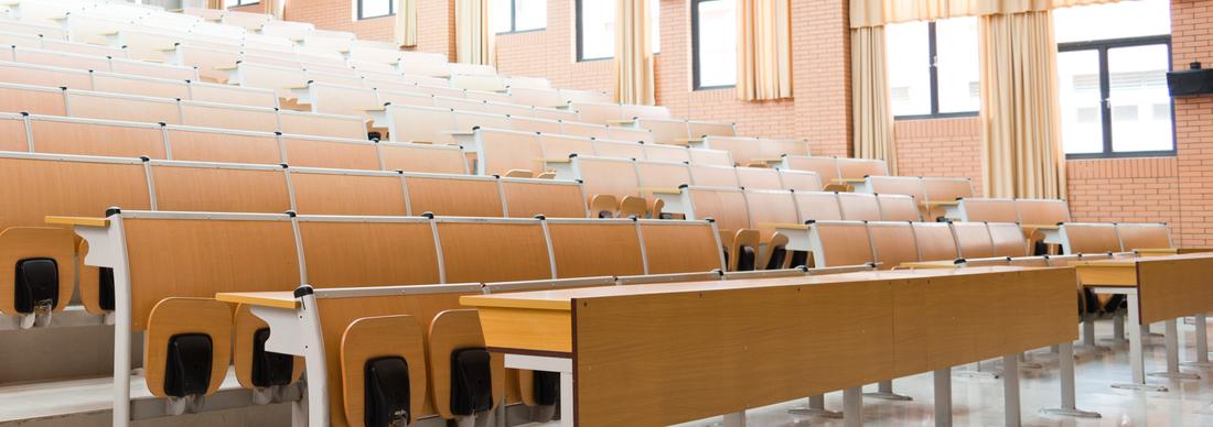Interior of a large lecture hall with rows of seats and tables at a college or university.