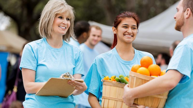 A group of volunteers collects healthy food at an outdoor event.