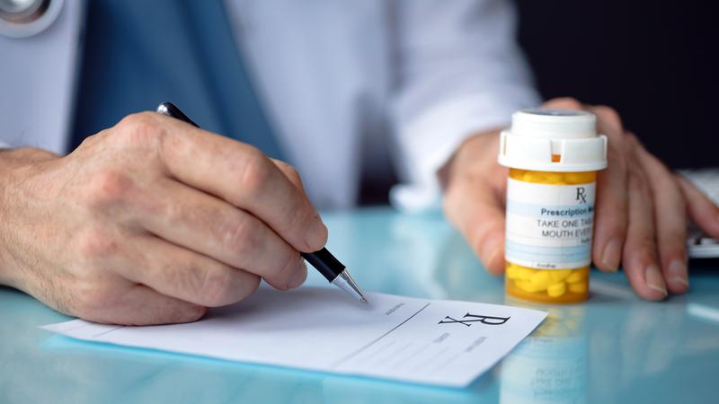 Close up photo of a doctor writing a prescription for a patient.