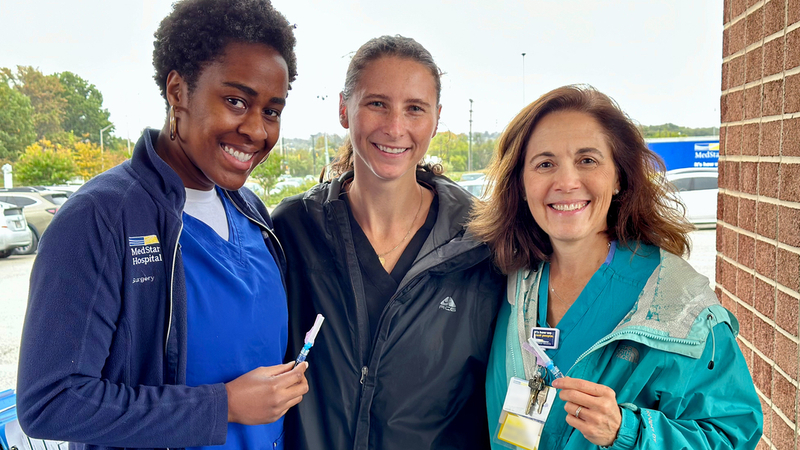 Healthcare professionals from MedStar Health administer flu vaccine shots at a drive-thru vaccine clinic.