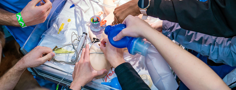 Close up of residents in the MedStar Health Emergency Medicine Residency Program simulating assisted breathing for an infant.