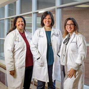 A team of 3 female physicians from MedStar Health stand together in a hallway in a hospital.