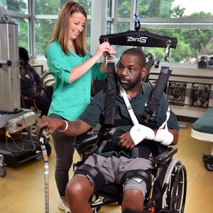 A provider from MedStar National Rehabilitation Hospital works with a patient, who is sitting in a wheelchair, using ZeroG equipment.