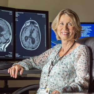 Dr Anette Virta-Paras poses in front of a set of brain scans at MedStar Health.