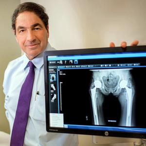 Dr James Tozzi poses for a photo with an xray in an exam room