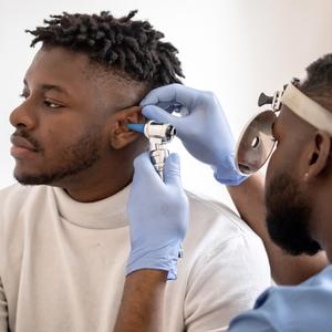 A doctor examines a patient's ear in a clinical setting.
