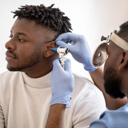 A doctor examines a patient's ear in a clinical setting.