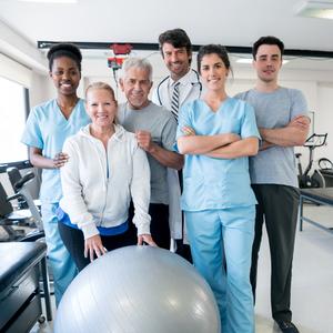 A team of physical therapists pose for a photo in a rehabilitation gym.