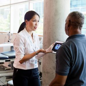 A female provider talks with a male patient in a rehabilitation gym.