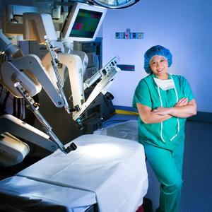 Dr Iglesia poses for a photo in front of a DaVinci robotic surgery machine at MedStar Health.