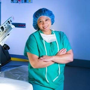 Dr Iglesia poses for a photo in front of a DaVinci robotic surgery machine at MedStar Health.