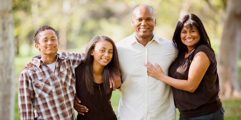 Guatemalan mother and African American father with two children family photo in park.