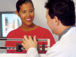 A doctor takes the blood pressure reading for an senior male patient in a clinical setting. The photo is taken from a high camera angle.