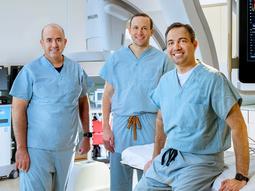 Doctors Itsik Ben-Dor, Brian Case and Hayder Hashim pose for a team photo in the cardiac catheterization lab at MedStar Washington Hospital Center.