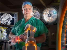 爱德华·奥利西（Edward Aulisi）博士在华盛顿医院中心的手术室里站着一个CIRQ机器人手臂。