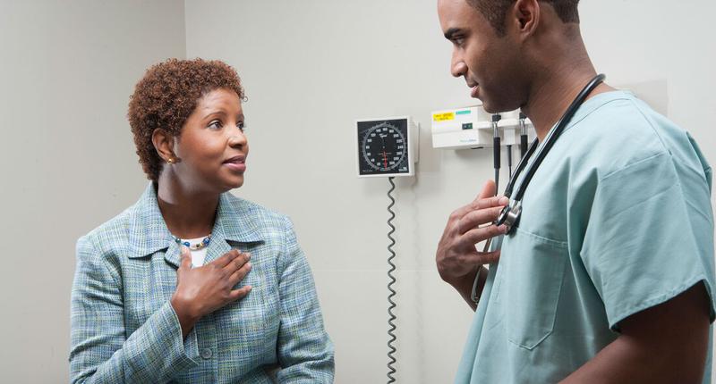 A female patient talks with her doctor in a clinical setting.