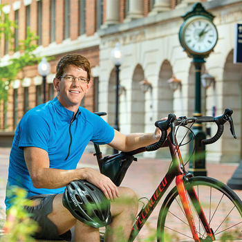 MedStar Orthopedice doctor Joseph Ferguson poses with his bike in an outdoor plaza.