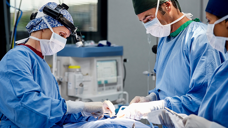 A team of surgeons perform a procedure in a hospital operating room.