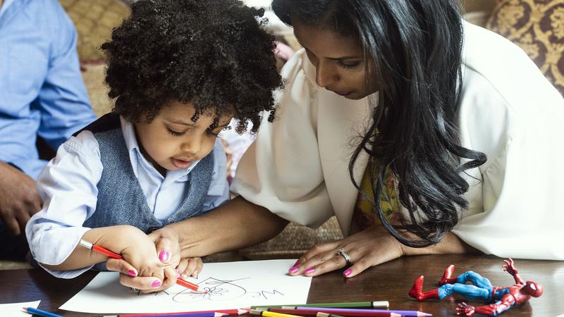 A woman and small child color together at home.