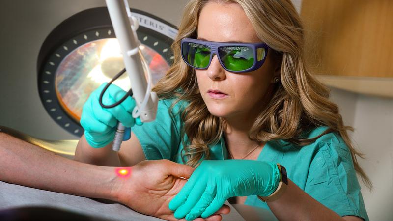 Dr Taryn Travis demonstrates the use of laser therapy equipment on on a patient's arm at MedStar Washington Hospital Center.