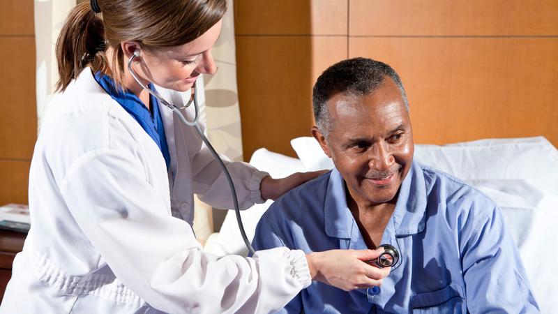 A doctor listens to a patient's heart in a clinical setting.