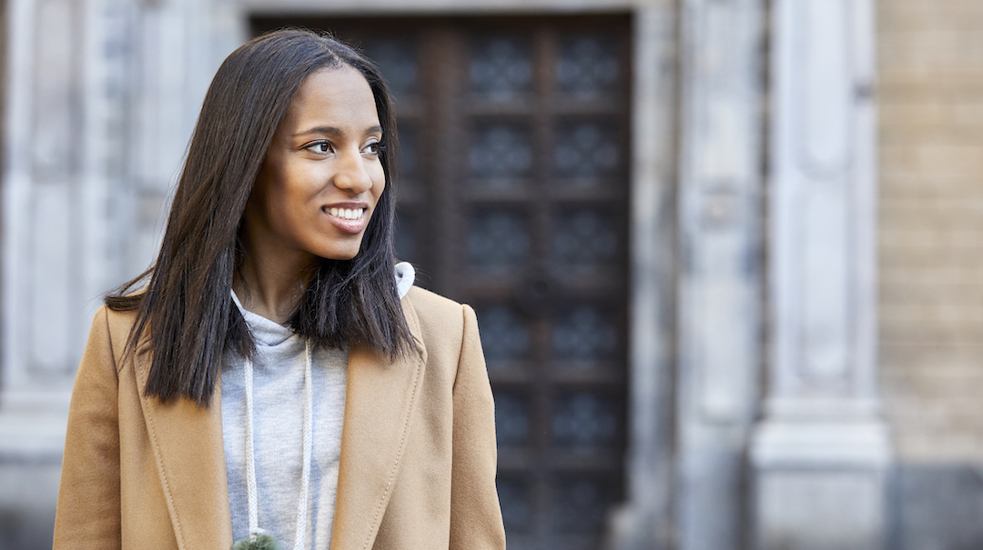 A young african american woman walks down a city street.