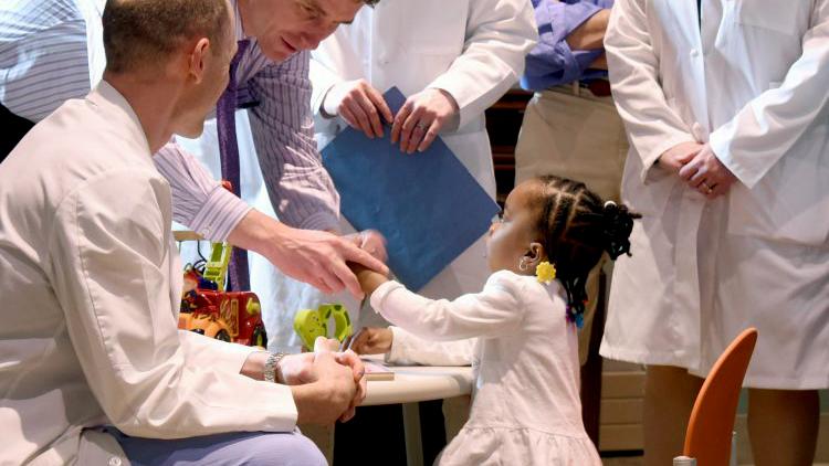 A group of doctors from the Curtis National Hand Clinic talks with a pediatric patient.