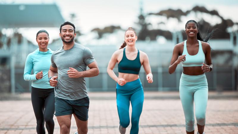 A group of young adults run outdoors.