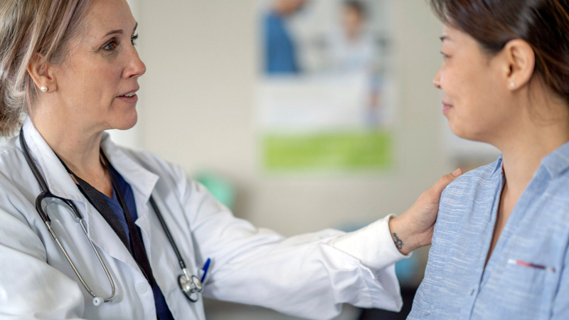 A doctor comforts a patient in a hospital setting.