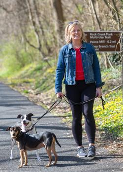 Tiffany Gannon walks her dogs outdoors in a park after undergoing successful treatment for breast cancer at MedStar Health.