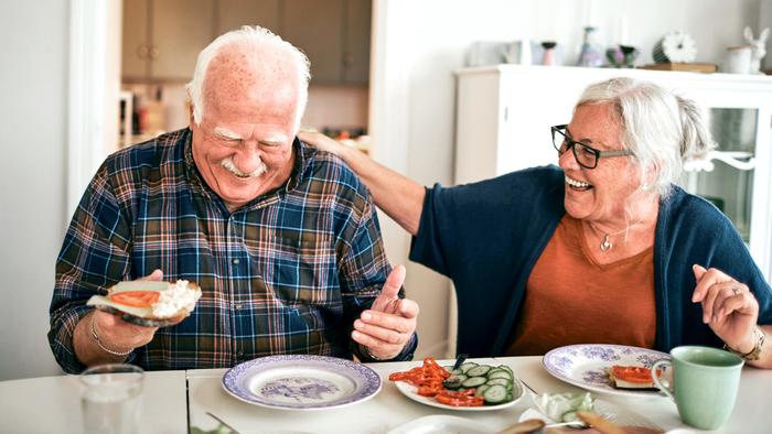 A senior couple eats a meal together in the kitchen at home.
