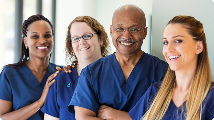 Four healthcare professionals stand together and pose for a photo.