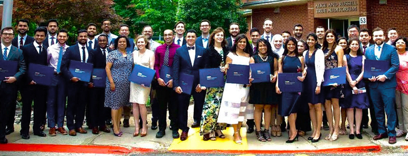 A class of graduates poses for a large group photo with their diplomas.