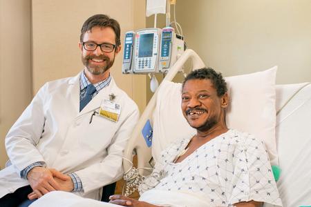 Dr. Hunter Groninger poses for a photo with a patient in a hospital room setting.