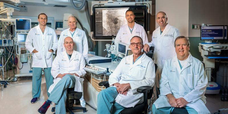 A team of MedStar cardiology doctors stand in a cardiac catheterization lab surrounded by modern technologic equipment.