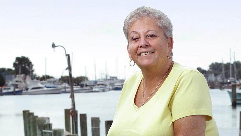 June Shepherd stands outside in front of a pier on the water, with the support of a cane, after a recent amputation.