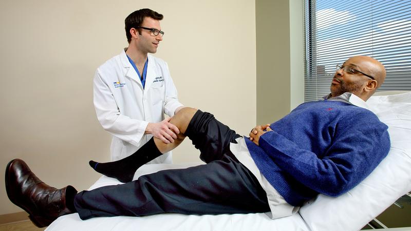 Dr Evan Argintar examine's a patient's knee during an office visit at MedStar Health.