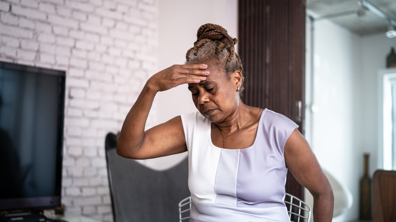 A woman holds her head because she is feeling sick.