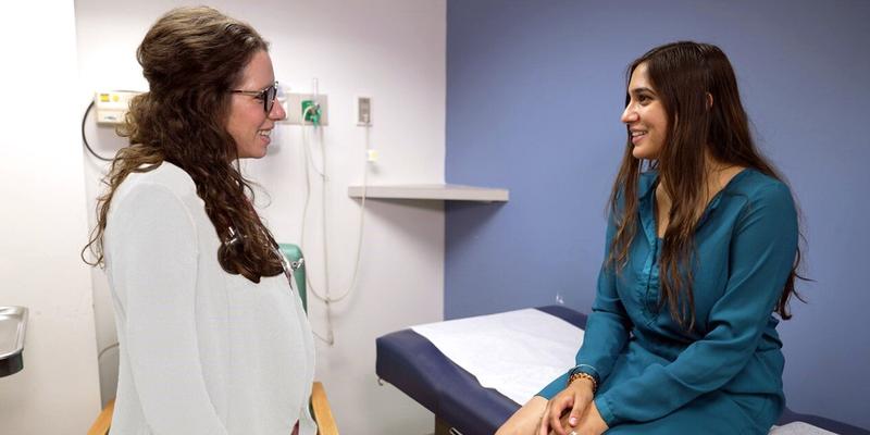 Dr Tara Santum consults with a female patient in a clinical setting.