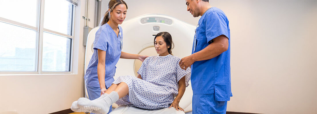 A medical team positions a patient in a diagnostic scanning machine.