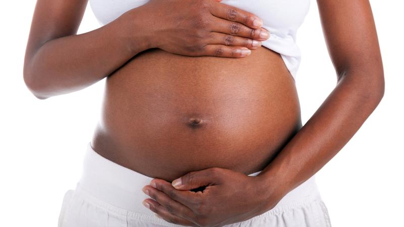 Close up photo of an African American woman's hands on her pregnant belly.