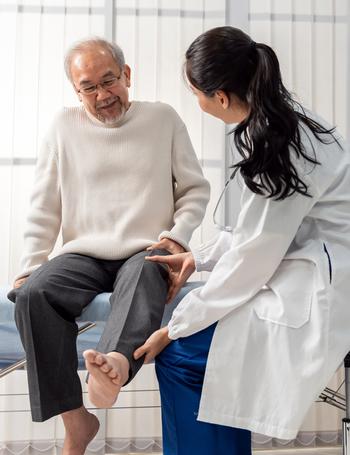 A doctor examines the leg of a male patient in a clinical setting.