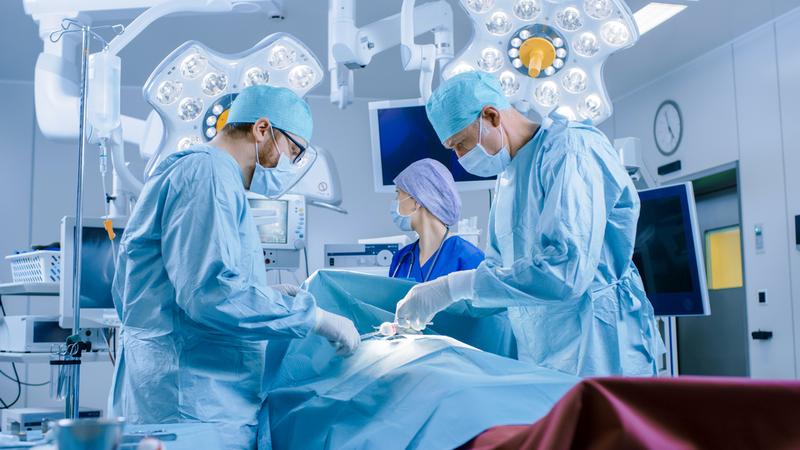 A team of medical professionals performs a medical procedure in an operating room.