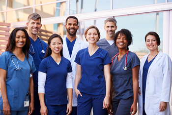 A group of medical professionals standing outside and smiling at the camera.